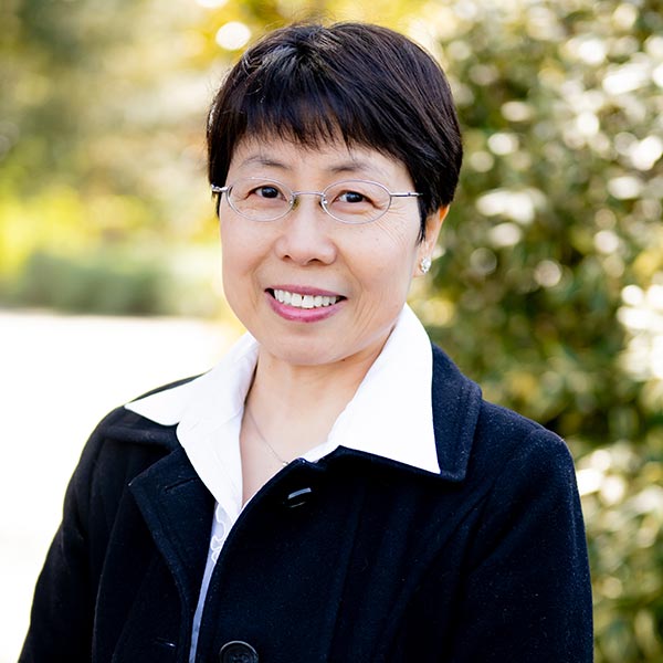 Professional woman with short dark hair wearing black blazer smiling outdoors
