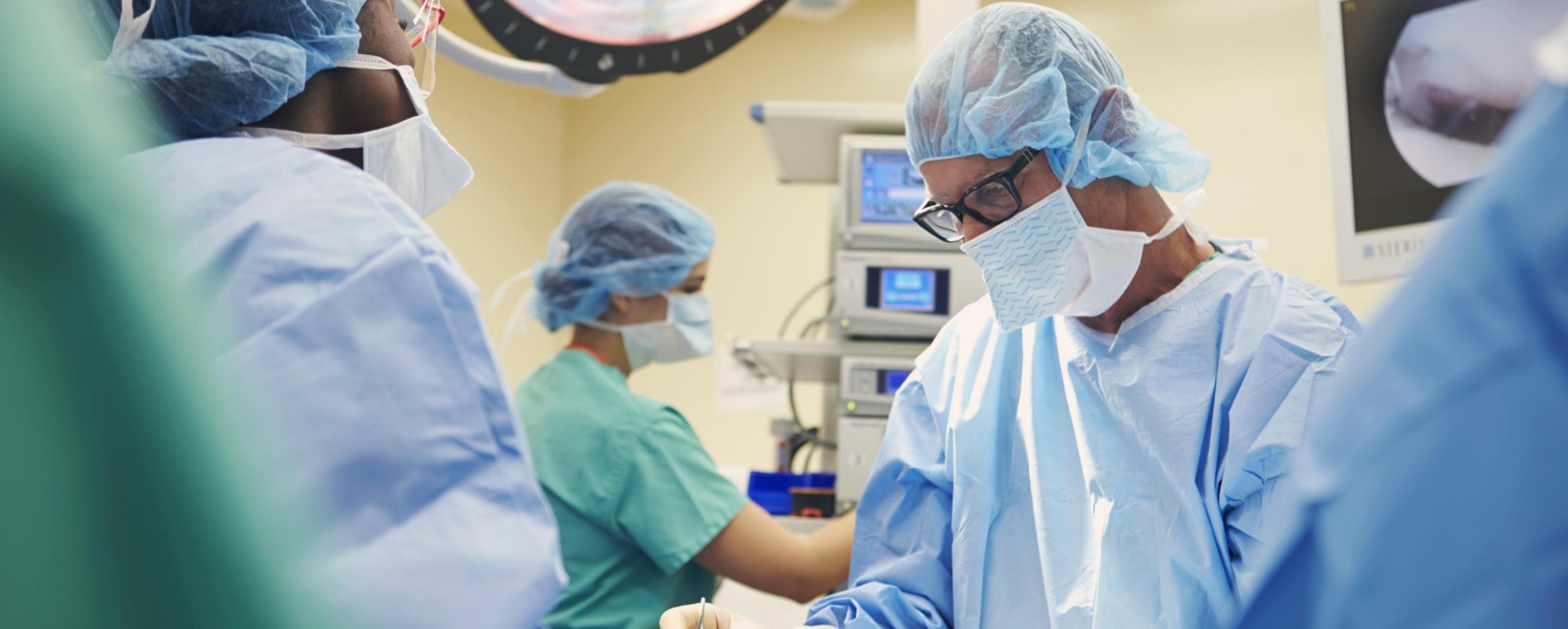 Medical professional in surgical attire performing a procedure in an operating room.