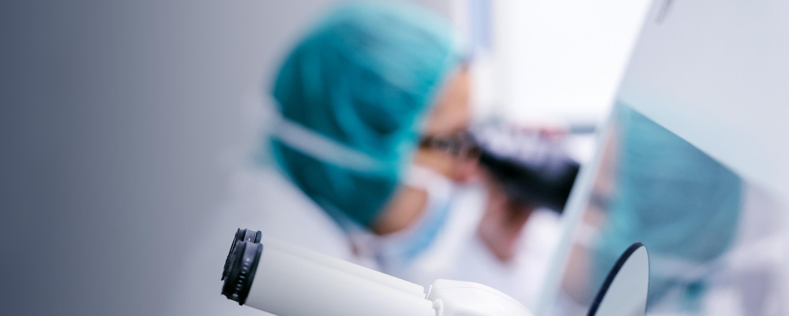 Medical professional in blue surgical cap and mask reviewing patient documents or medical charts.